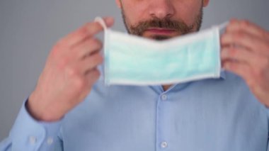 Covid-19 koronavirüsünün pandemik koruması. Tıbbi maske takmış sakallı beyaz bir adamın portresi. Virüs koruması.