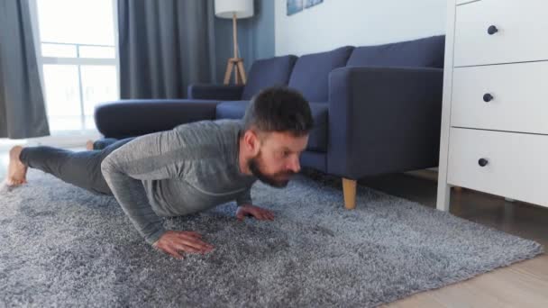 Hombre caucásico hace flexiones en casa durante la cuarentena debido a COVID-19 — Vídeos de Stock