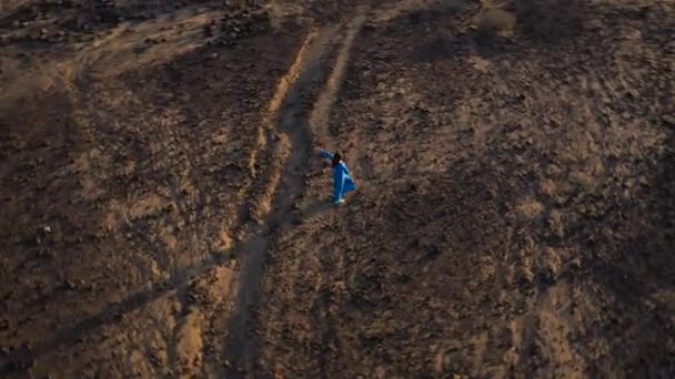Vue aérienne de la femme vêtue d'une robe bleue tournée, les bras tendus sur les côtés, au milieu du désert. Tenerife, Îles Canaries, Espagne 