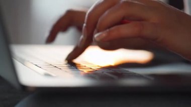 Dişi eller batan güneşe karşı dizüstü bilgisayarda klavye kullanıyor. Uzak çalışma kavramı.