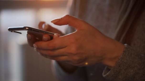 Mani femminili utilizzando lo smartphone contro il sole al tramonto. — Video Stock