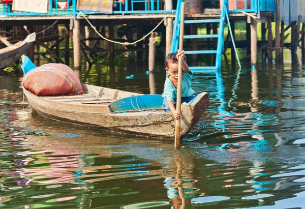 Um rapaz não identificado num barco a flutuar no lago Tonle Sap — Fotografia de Stock