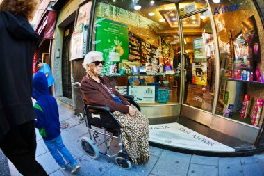 An elderly woman in a wheelchair in the street clipart