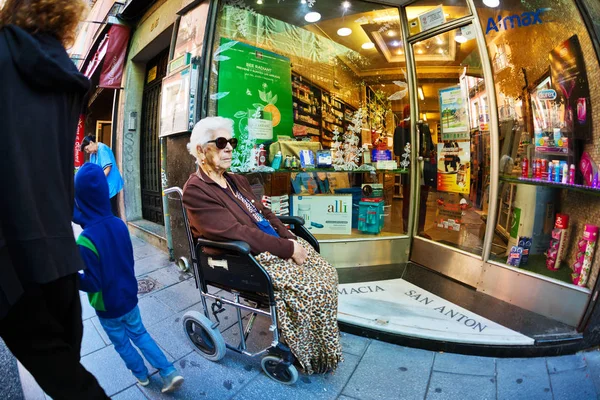 Una donna anziana su una sedia a rotelle per strada — Foto Stock