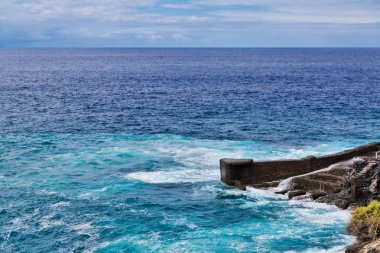Deniz kasvetli gökyüzü altında kayalarda