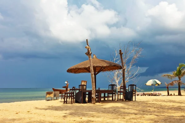 Wooden chairs and umbrellas on white sand beach — Stock Photo, Image