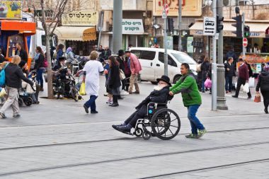 genç adam bir tekerlekli sandalyede taşımak için yardımcı olur
