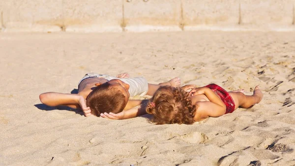 Broer en zus zonnen op een zandstrand en talk — Stockfoto