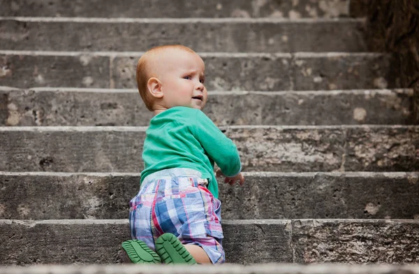 Little boy kneels on a stone staircase — Stock Photo, Image