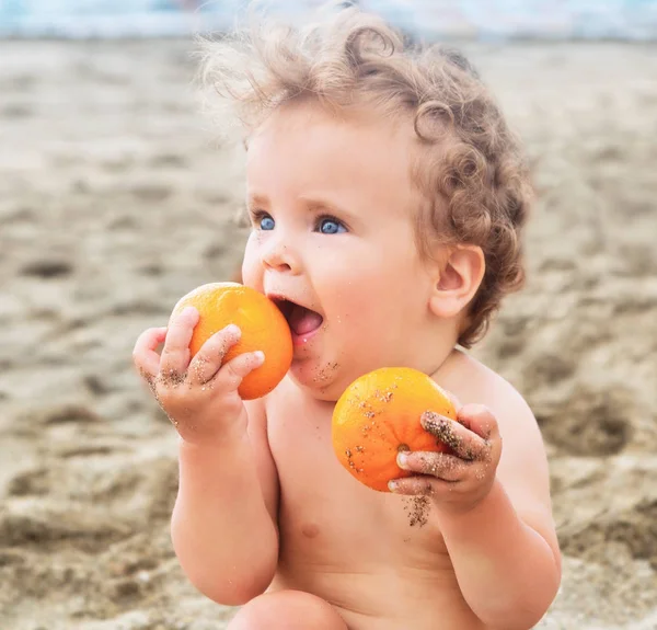 甘いオレンジ色の果物と小さな女の赤ちゃん. — ストック写真