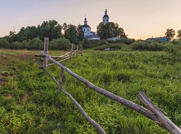 Venkovský ortodoxní kostel při západu slunce před zelenou loukou — Stock fotografie