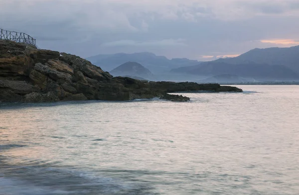 Bela vista da praia rochosa durante o pôr do sol . — Fotografia de Stock