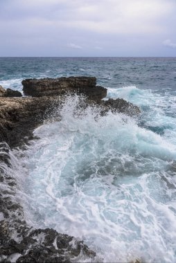 Kasvetli bir dramatik gökyüzü altında kayalık plaj