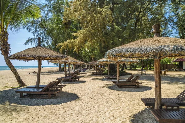 Wooden chairs and umbrellas on white sand beach — Stock Photo, Image