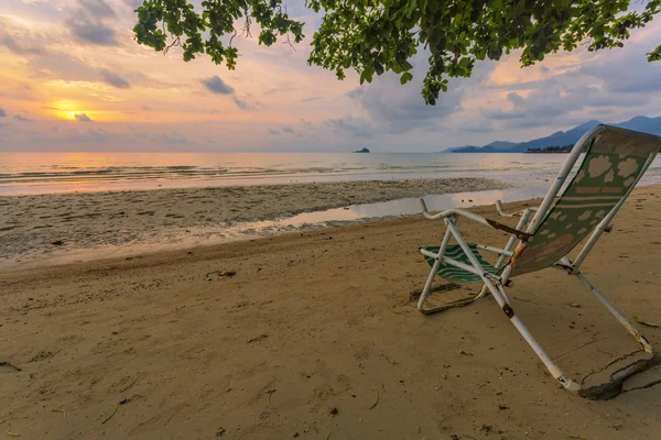 Πτυσσόμενη καρέκλα στην αμμώδη ακτή της θάλασσας το ηλιοβασίλεμα — Φωτογραφία Αρχείου