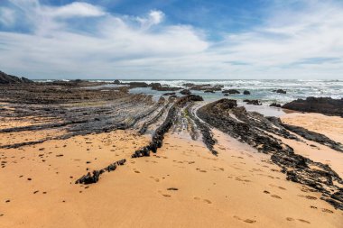 Aljezur 'daki Amoreira Sahili' nde mavi gökyüzünün altında kaya oluşumları. Portekiz