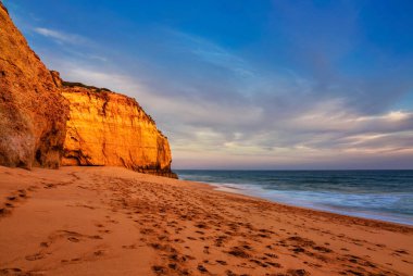 Kayalıkların ve Ferragudo yakınlarındaki sahil manzaralı gün batımı manzarası. Portekiz
