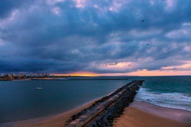 Pier 'den ünlü eski Farol de Portimao molhe este' ye kasvetli günbatımının altında. Portekiz