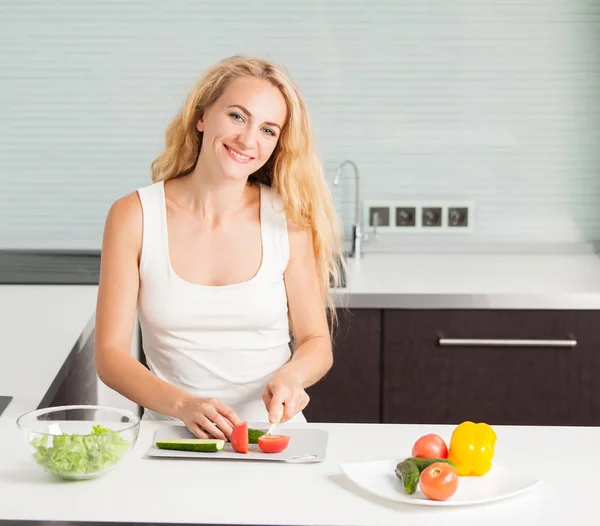 Ung kvinna förbereder grönsakssallad — Stockfoto