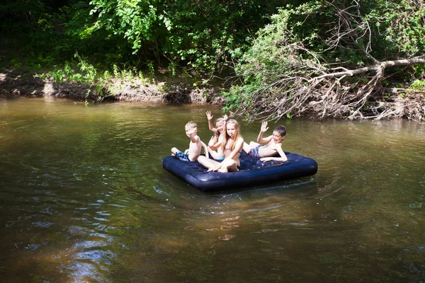 Niños flotando en el río — Foto de Stock