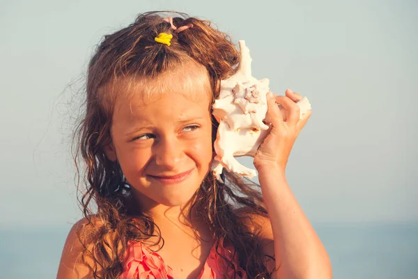 Child put the shell to her ear — Stock Photo, Image