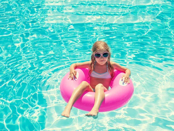 Yüzme havuzunda şişme yüzük takan kız.
