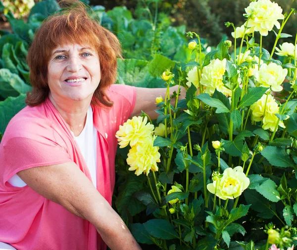 Mulher no jardim cuida de flores — Fotografia de Stock