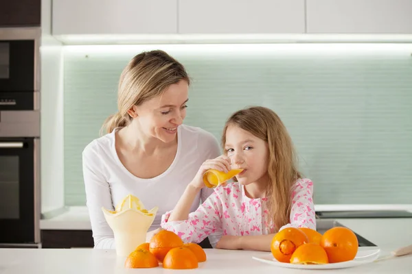 Anne ve kızı meyve sıkacağında portakal suyu yapıyorlar. — Stok fotoğraf