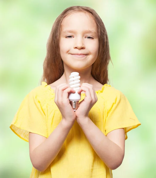 Девушка держит энергосберегающую лампу — стоковое фото