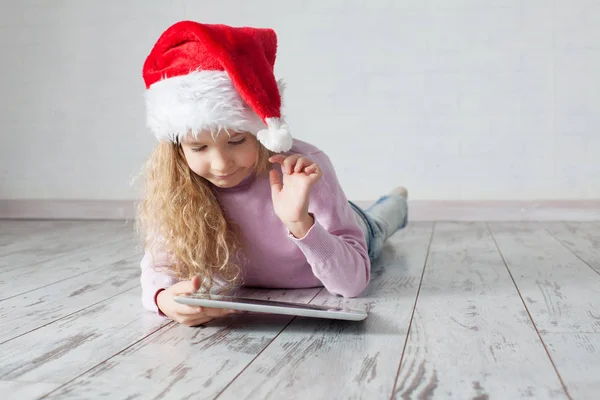 Ребенок в рождественской шляпе с планшетом — стоковое фото