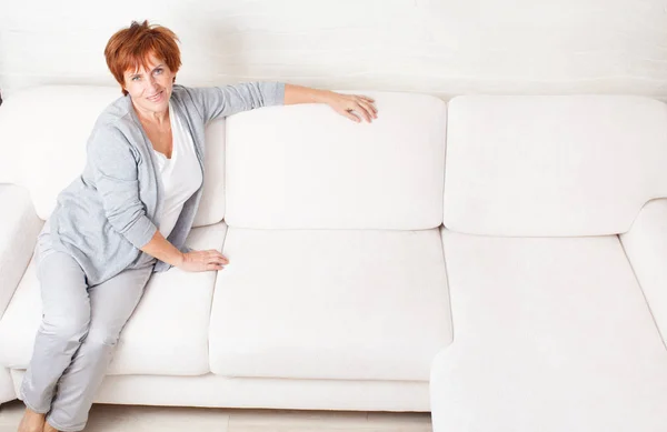 Счастливая зрелая женщина на диване — стоковое фото