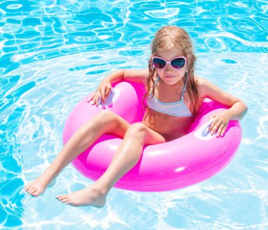 Yüzme havuzunda şişme yüzük takan kız.