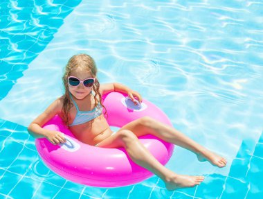 Yüzme havuzunda şişme yüzük takan kız.