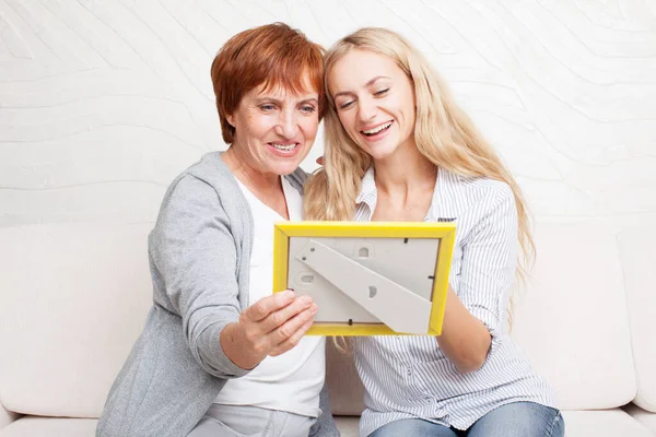 Mor med dotter tittar på fotoram — Stockfoto