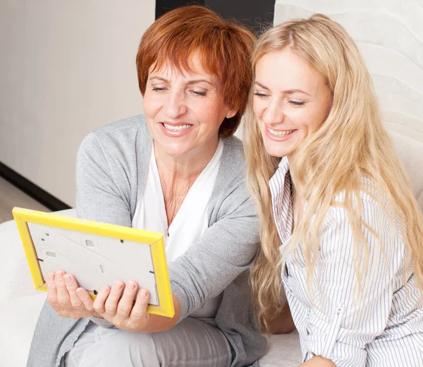 Mother with daughter looking at photo frame — Stock Photo, Image