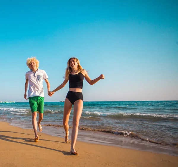 Glada unga par att ha kul på stranden på solig dag — Stockfoto