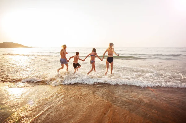 Gelukkige jongeren hebben plezier op het strand op zonnige dag — Stockfoto