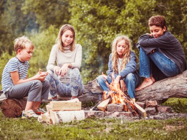 Çocuklar kampta, ateşin yanında.