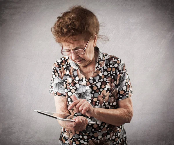 Gammal kvinna som håller en tablett i händerna på — Stockfoto