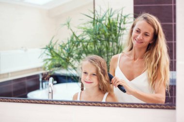 Anne kızın saçını tarıyor.