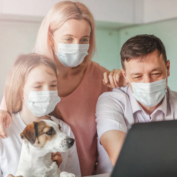 Familia feliz mirando a la computadora portátil en la máscara durante la pandemia coronavirus — Foto de Stock