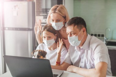 Mutlu aile, pandemik koronavirüs sırasında evde maskeli dizüstü bilgisayar arıyor.