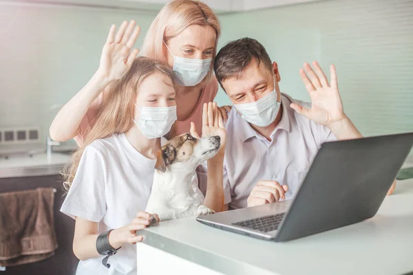 Happy family looking to laptop at home in mask during the pandemic coronavirus — Stock Photo, Image