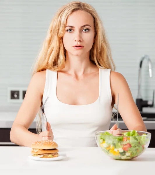 Mulher escolhe entre um alimento saudável e não saudável — Fotografia de Stock