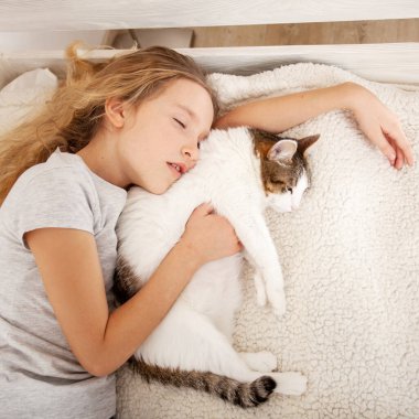 Çocuk kediyle yatıyor.