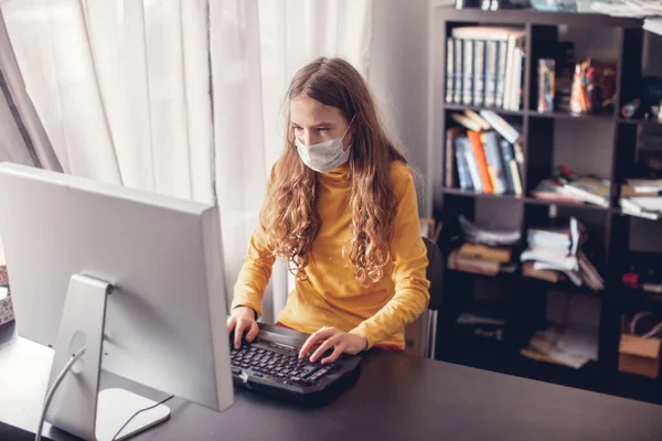 Teen gaming at home with computer, wearing protective mask