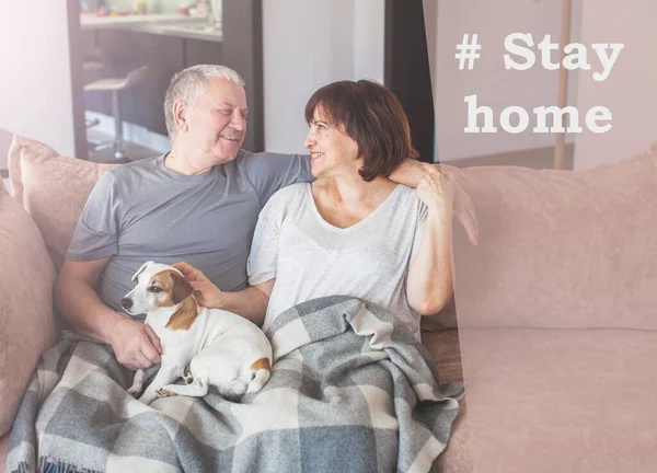 Feliz pareja de ancianos sentados en el sofá en casa durante la pandemia coronavirus — Foto de Stock