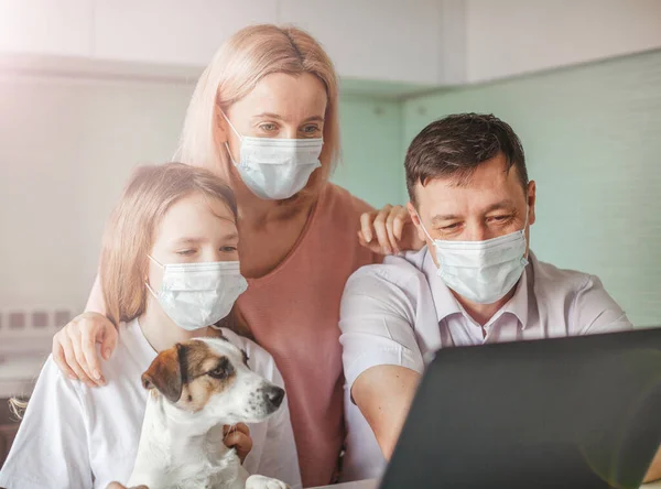 Happy family looking to laptop in mask during the pandemic coronavirus — Stock Photo, Image