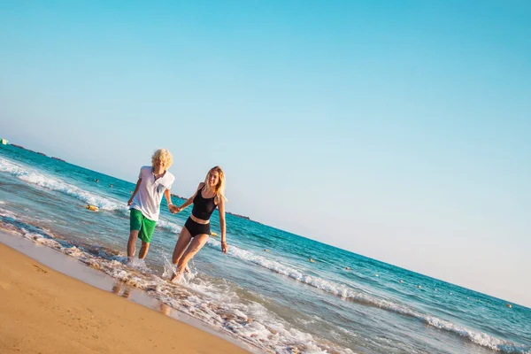 Счастливая молодая пара веселится на пляже в солнечный день — стоковое фото