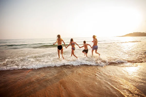 Счастливые молодые люди веселятся на пляже в солнечный день — стоковое фото